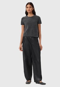 Grå kortærmet strikket sweater, parret med løse sorte læderbukser og flade sorte sko med hvide prikker. Enkel og moderne design.