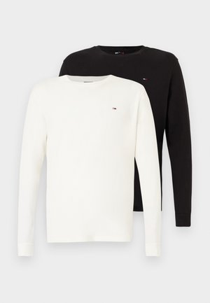 Două tricouri cu mânecă lungă și guler rotund, unul alb și unul negru, fiecare având un mic logo rectangular pe piept.