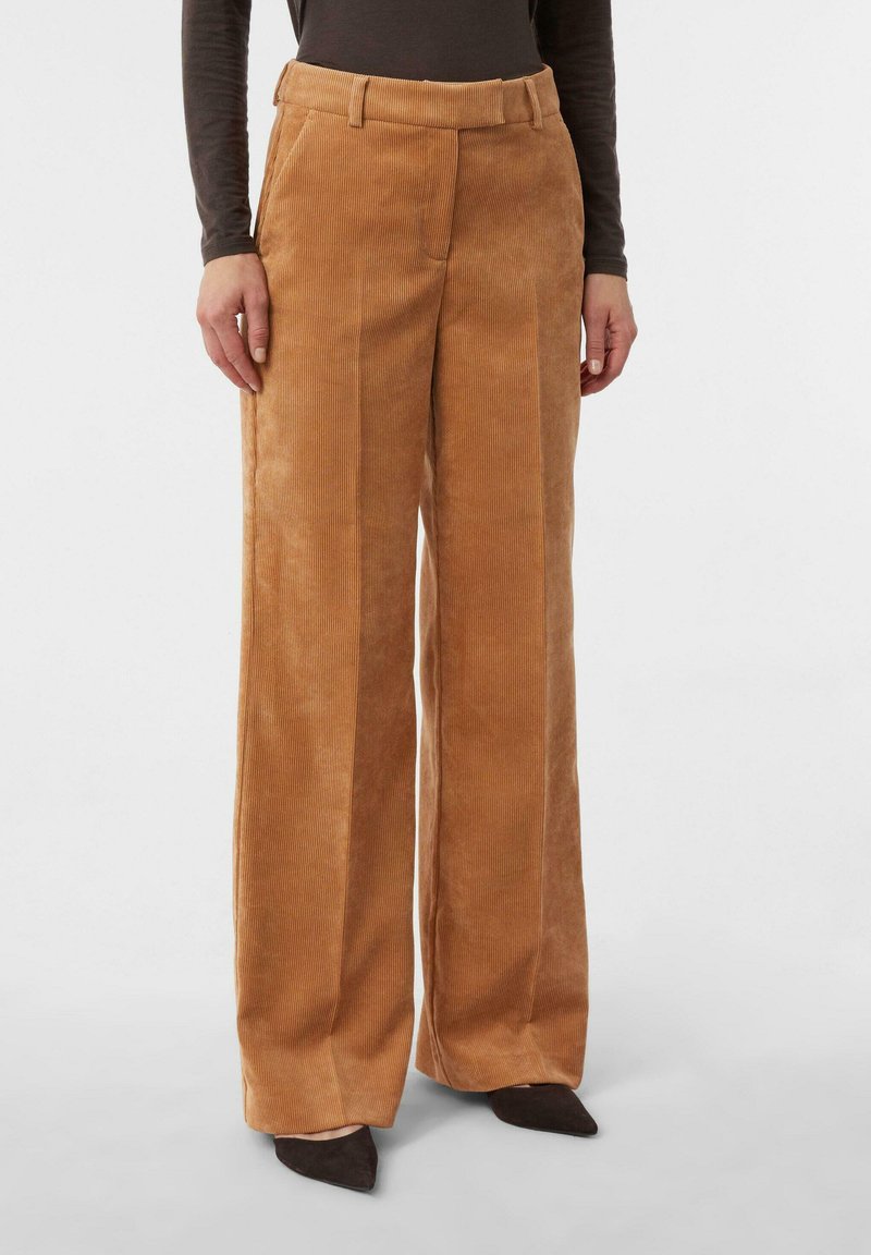 Szerokie spodnie ze sztruksu w bogatym, karmelowym kolorze, z teksturowanymi żeberkami, bocznymi kieszeniami i paskiem w talii. Odpowiednie na co dzień lub na formalne okazje.