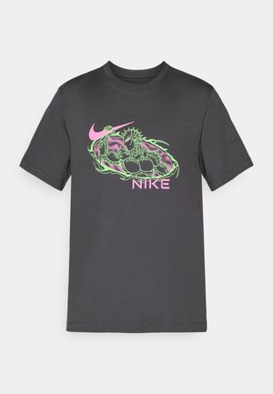 T-shirt Nike gris foncé avec un graphique vert et rose d'un dragon musclé tenant un swoosh Nike rose et un texte Nike rose en dessous.