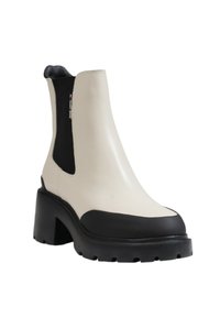 Bílá kožená Chelsea obuv s černou gumovou podrážkou a podpatkem. Boční elastický panel a strukturované detaily. Zaoblená špička.