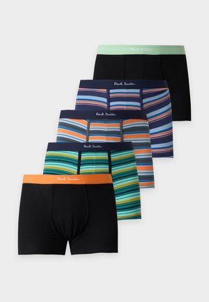 Homme adulte musclé debout, pieds nus, portant un boxer noir avec une ceinture de couleur claire sur un fond blanc uni.