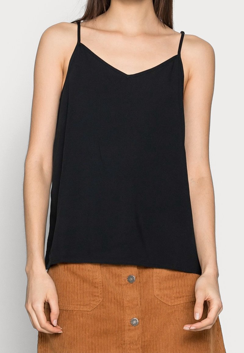 Czarna beżrękawnikowa bluzka z dekoltem w serek i cienkimi ramiączkami, wykonana z miękkiego materiału, noszona z szortami z materiału sztruksowego z przednimi kieszeniami.