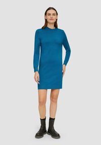 Sukienka dzianinowa w jaskrawym niebieskim kolorze, z długimi rękawami, okrągłym dekoltem i dopasowanym krojem, zestawiona z czarnymi botkami za kostkę. Gładka faktura i prosty design.