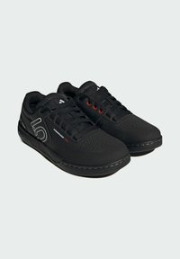 Sneakers neri con tomaia in tessuto testurizzato, dettagli rossi sui lacci e suola in gomma con un leggero motivo di battistrada per una migliore aderenza.