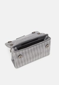 Černobílá vzorovaná látková taška s kovovými zapínáními na cvočky. Obdélníkový tvar s vnitřními přihrádkami pro lepší organizaci.