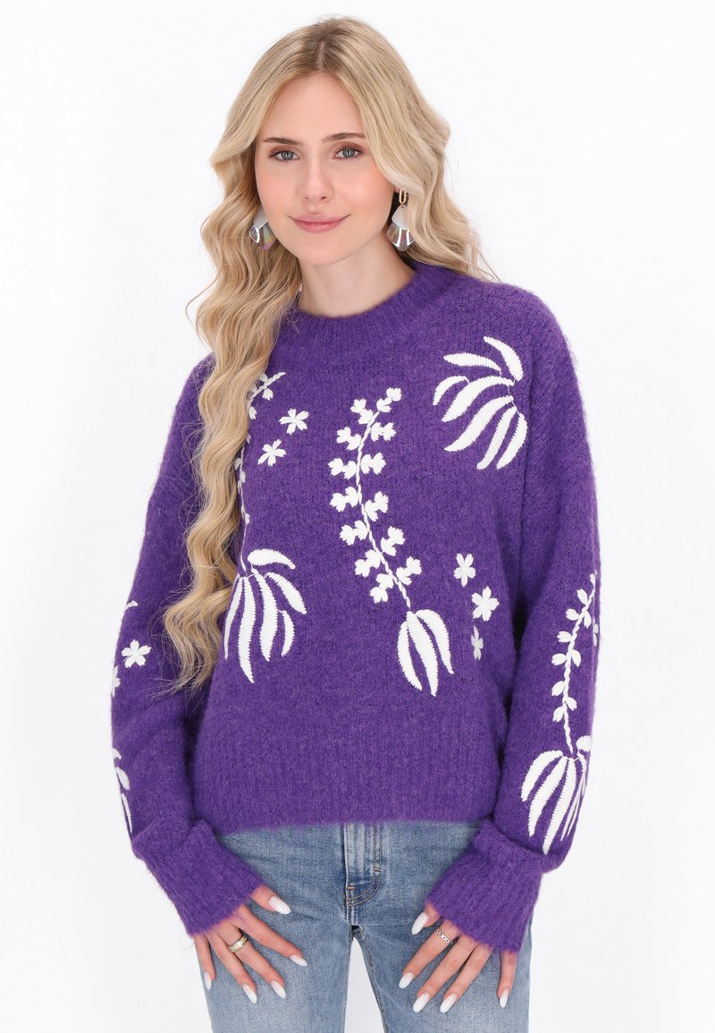 Violetti neulepaita, jossa on valkoista kukka-embroiderya, pyöreä pääntie, rento istuvuus ja pitkät hihat, joissa on pidennetyt hihansuut.