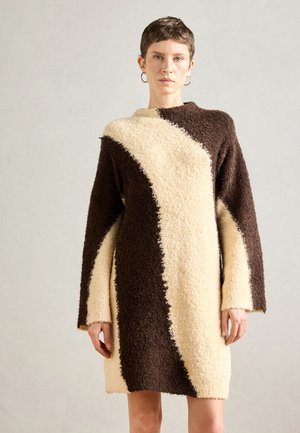 Knit dress featuring a diagonal color-block design in dark brown and cream. Soft, textured fabric with long sleeves and round neckline.