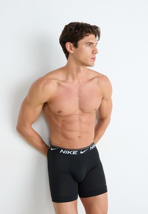 Zwarte Nike boxershorts met een slim fit ontwerp en een elastische tailleband met een wit logo. Gladde textuur en een lengte tot halverwege de dijen.