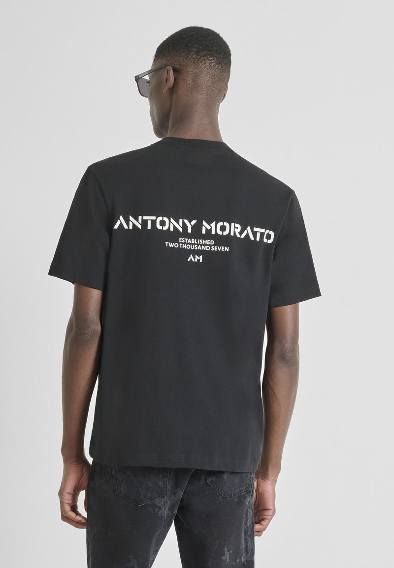 Camiseta negra de algodón de manga corta, con texto impreso en blanco en la parte posterior: "ANTONY MORATO ESTABLECIDO DOS MIL SIETE A.M."