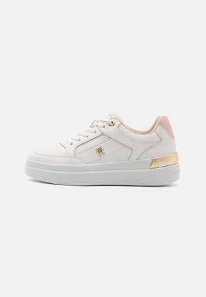Zapatilla de cuero blanco con acentos dorados y rosas, suela plana, diseño con cordones y detalle del logo en el lateral. Textura suave en toda su superficie.