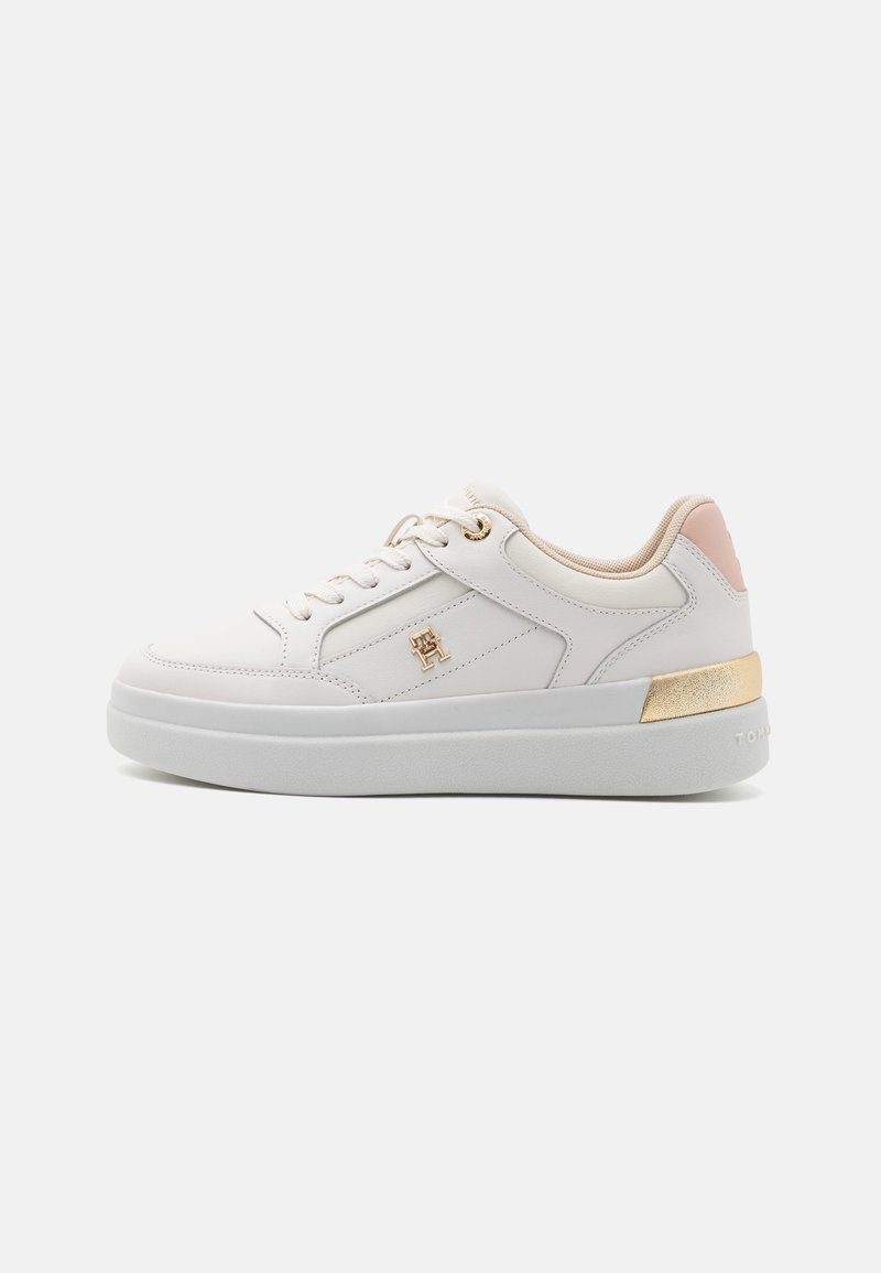 Zapatilla de cuero blanco con acentos dorados y rosas, suela plana, diseño con cordones y detalle del logo en el lateral. Textura suave en toda su superficie.