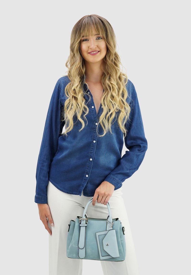 Denim shirt met knopen aan de voorkant, lange mouwen en een relaxte pasvorm; houdt een lichtblauwe handtas vast met een afneembare zak en zilveren hardware.