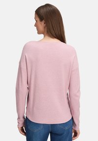 Helles rosa Langarmpullover mit lockerer Passform, rundem Ausschnitt und strukturiertem Rippdesign. Weiches Material mit überschnittenen Schultern und asymmetrischem Saum.