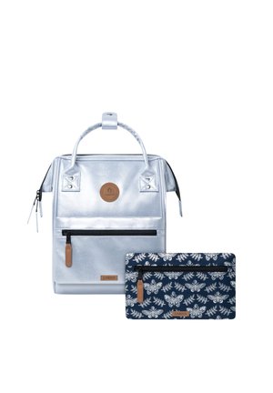 Silberner Rucksack mit oberen Griffen und vorderer Reißverschlusstasche neben einem marineblauen Reißverschluss-Etui mit weißen Schmetterlings- und Blattmustern.