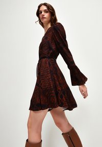 Braun gemustertes Kleid mit kurzen Ärmeln, tailliertem Bund, schwingendem Rock und Glockenärmeln. Es besteht aus einem weichen, leichten Stoff und hat ein strukturiertes Design.