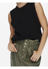 Black sleeveless knitted top paired with a green elastic-waist skirt featuring snap button accents and a side pocket.