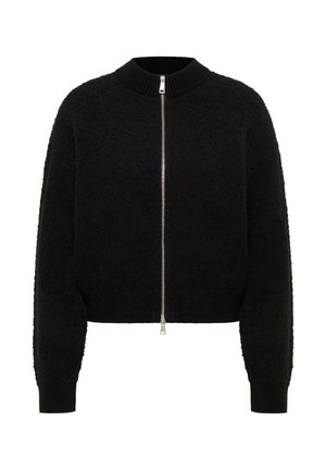 Melna īsā jaka ar pūkainu tekstūru, tai ir augsts apkaklis, pilna garuma rāvējslēdzējs un ribota aproce un apakša.