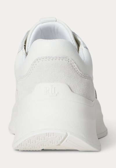 Vue arrière d'une chaussure de sport blanche en daim et cuir avec une semelle épaisse comportant une empreinte de logo discrète.