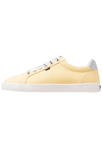 Yellow canvas sneaker with white rubber sole, featuring gray heel accent and lace-up closure with metal eyelets.