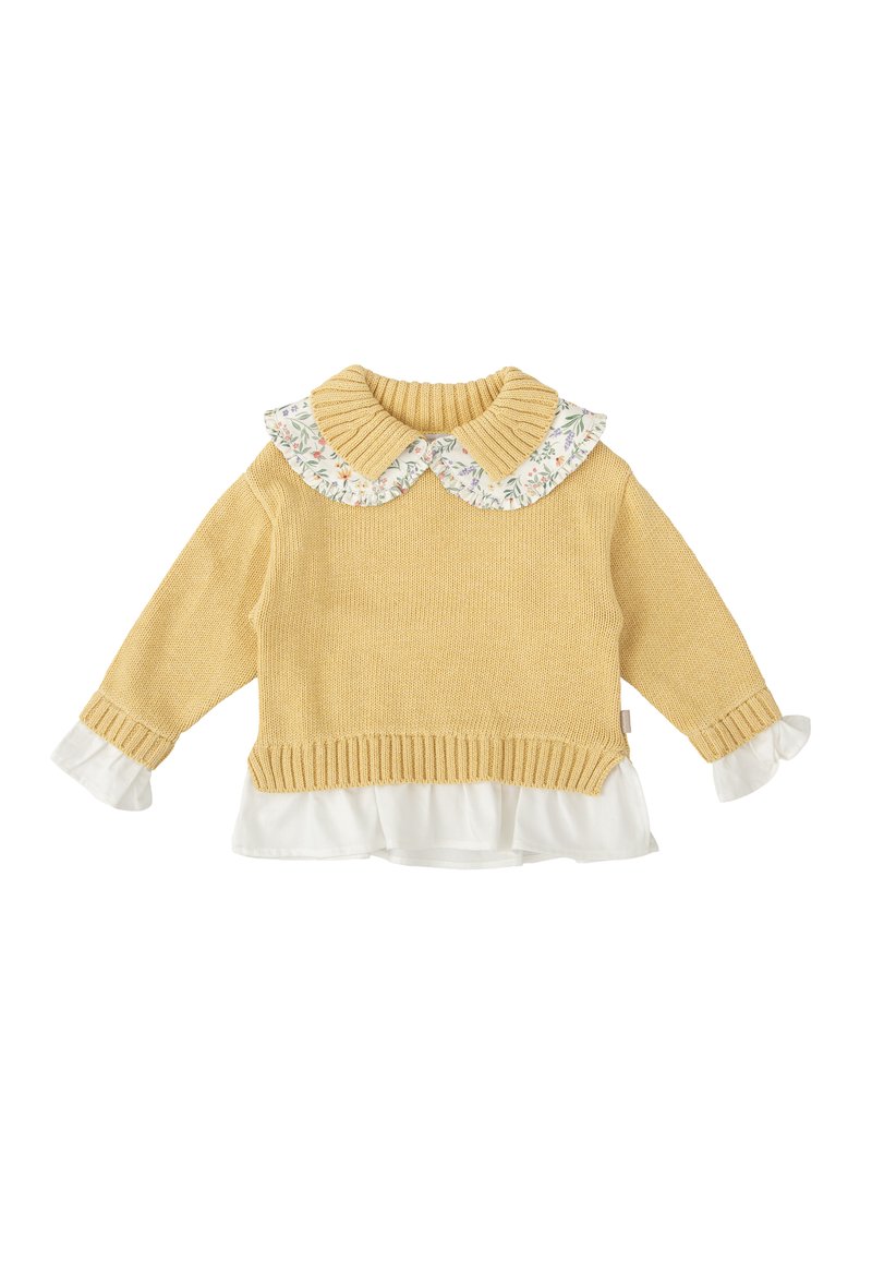 Suéter amarillo de punto con cuello de canalé y blusa blanca con estampado floral y volantes debajo. Mangas largas con acentos de puño blanco.