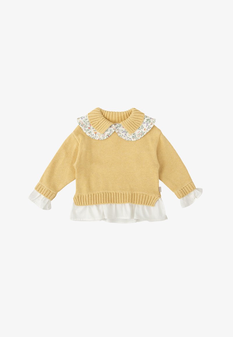Pull en tricot jaune avec un col côtelé et une blouse blanche à fleurs froncée en dessous. Manches longues avec des accents de poignet blancs.
