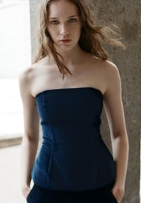 Tamnoplavi top bez naramenica s uskim korzetom i strukturiranim dizajnom. Tekstuirana tkanina sa šavovima koja pruža krojeni oblik. Minimalistički stil.