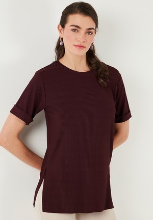 Burgundy ribbed t-shirt with short sleeves, crew neckline, side slits, and rolled cuffs, made from a soft, textured fabric.