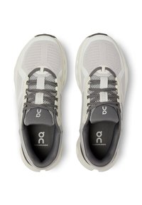 Scarpe da corsa grigio chiaro con tomaia in mesh, linguetta imbottita e suola spessa con branding sottile e accenti grigi sui lacci.