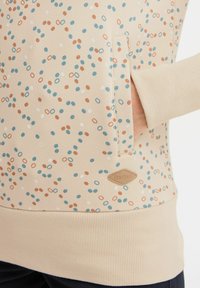 Felpa beige con motivi circolari e ovali colorati in blu e ruggine. Include una tasca laterale e polsini a costine.