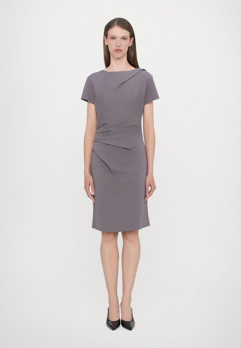 Short-sleeve, fitted gray dress with ruching detail at the waist. Smooth texture and knee-length cut, paired with black high-heeled shoes.