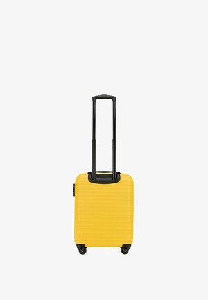 Hartschalen-Koffer in Gelb mit strukturierten Rillen, ausziehbarem schwarzen Griff und vier Rädern für Mobilität. Kompaktes Design für Reisen.