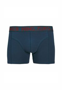 Marineblaue Boxer Shorts mit einem kontrastierenden burgunderfarbenen Bund, der den Text "NIN.7.ZERO." trägt. Schlichte Textur, körpernahe Form und mittelhoher Schnitt.