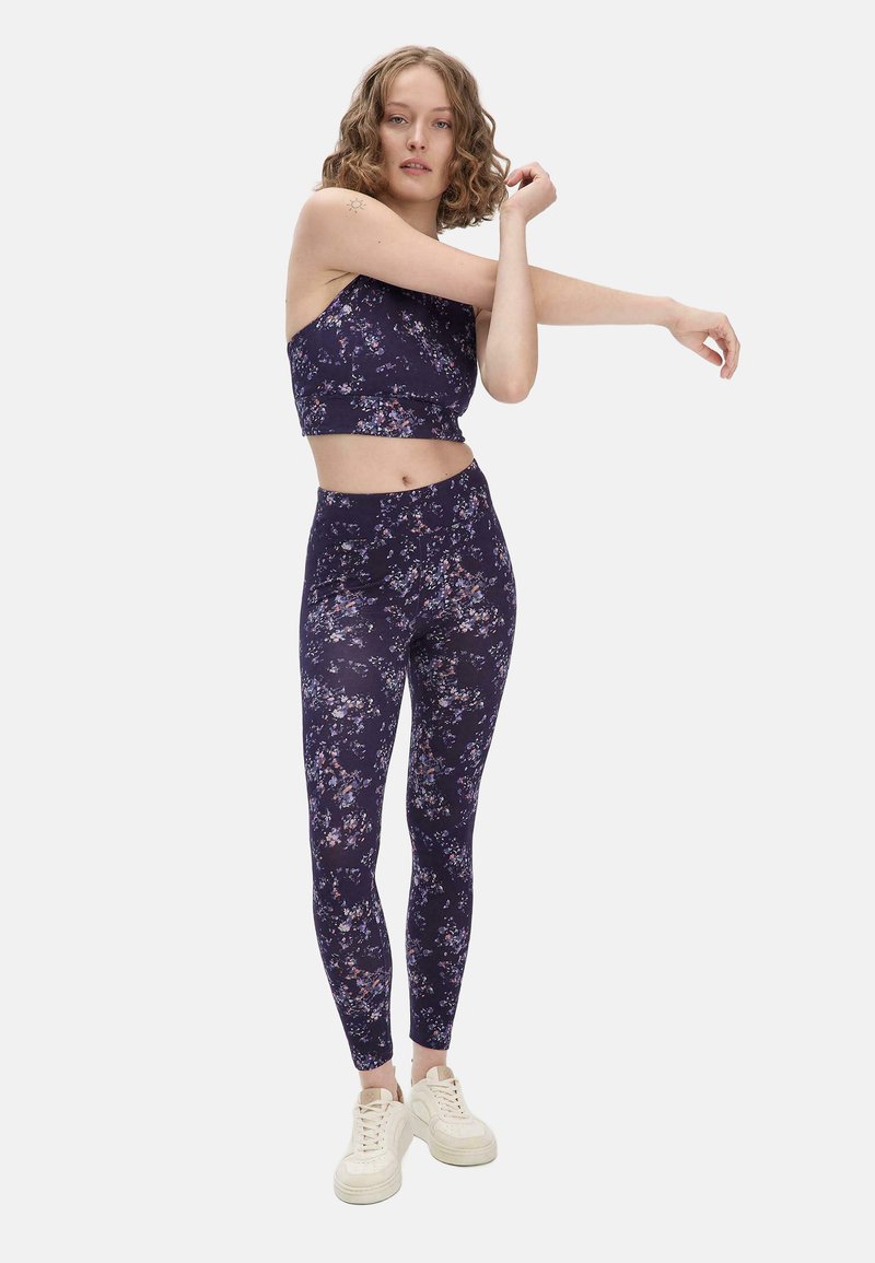 Bloemen sportset bestaande uit een donkerpaarse crop top en bijpassende leggings, beide met een zachte textuur en ingewikkelde bloemmotieven.