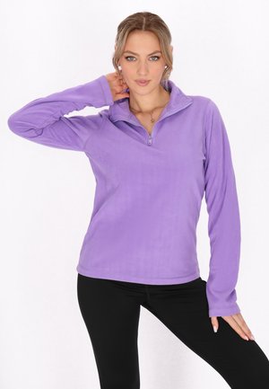 Lilla fleece pullover med en kvart lynlås, der har lange ærmer og en blød tekstur. Parret med sorte leggings.