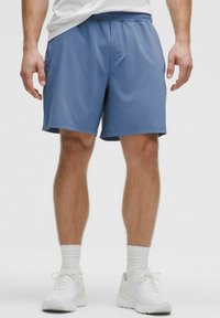 Pantalones cortos deportivos azules de tejido ligero cuentan con una cinturilla elástica y bolsillos laterales, combinados con zapatillas blancas y calcetines.