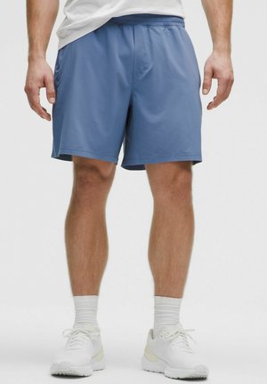 Pantaloni sportivi blu realizzati in tessuto leggero con una fascia in vita elastica e tasche laterali, abbinati a scarpe da ginnastica bianche e calzini.