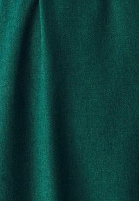 Dunkelgrüner Stoff mit glatter Textur, der einen leichten Glanz und ein gleichmäßiges Strickmuster aufweist. Das Material wirkt schwerelose und weich.