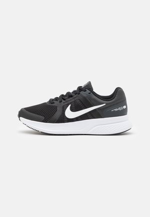 Czarny but do biegania Nike z białą podeszwą i białym logo Nike Swoosh z boku, wyposażony w oddychającą siateczkową cholewkę i wiązanie na sznurówki.