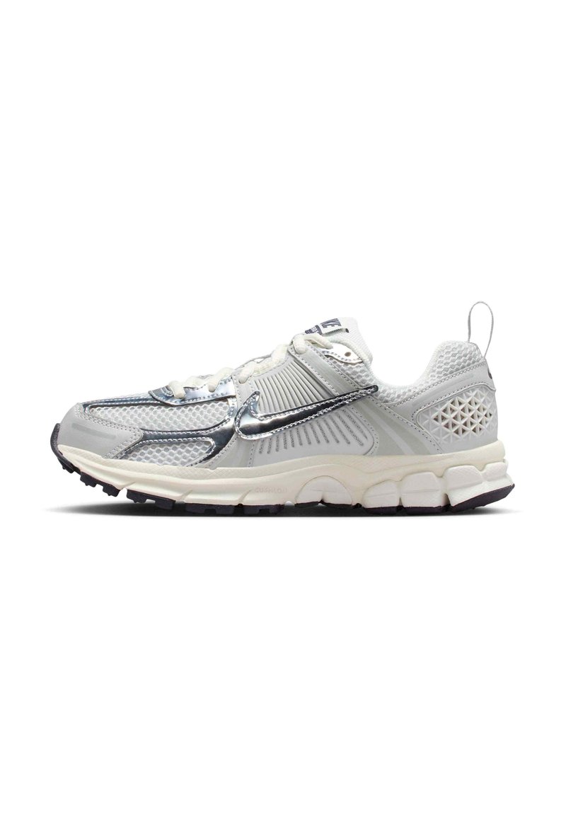 Chaussure de sport grise avec une tige en mesh, accents métalliques, panneaux latéraux texturés et une semelle en caoutchouc robuste avec adhérence.