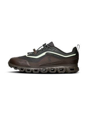 Baskets de sport marron foncé et noires avec bande vert clair, semelle épaisse et rembourrée, tige en mesh et lacets à serrage rapide, montrées de profil latéral.