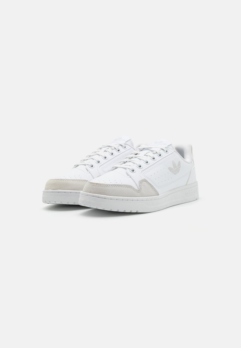 Witte sneakers van glad leer met suède accenten, geperforeerde details, platte veters en een gestructureerde rubberen zool. Subtiele branding aan de zijkant.