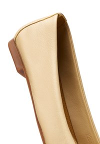 Chaussure plate beige en cuir avec bout arrondi et petit talon marron, vue de côté sur fond blanc.