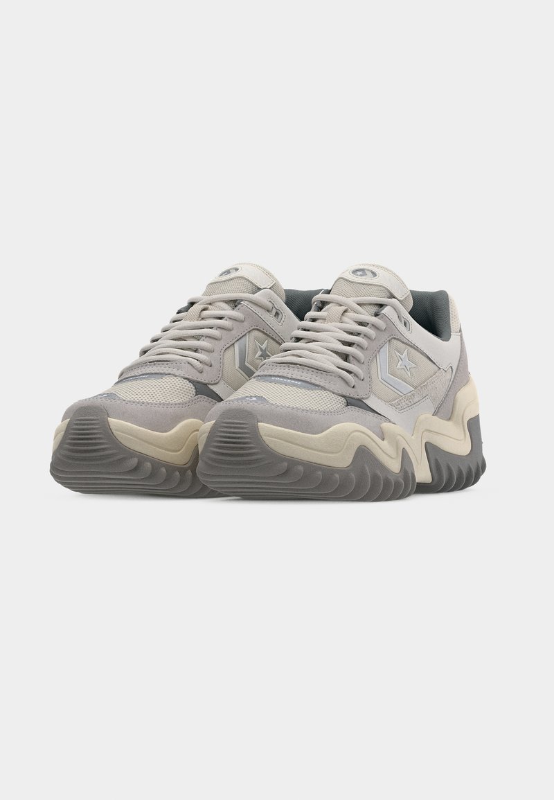 Coppia di sneakers Converse beige e grigie con suole spesse ondulate, logo a stella sul lato e lacci, viste di fronte su sfondo bianco.
