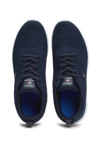 Baskets bleu marine avec tige en tricot texturé, design à lacets, semelle blanche, arborant le logo Tommy Hilfiger sur la languette et en accent au niveau du talon.