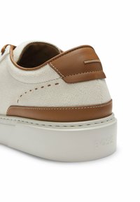 Baskets blanches texturées avec garniture en cuir fauve, semelle blanche et logo "BOSS" embossé sur le talon.