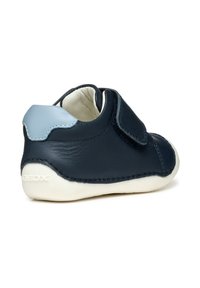Scarpa in pelle blu navy con un accento azzurro chiaro, dotata di una fascia in Velcro, forma arrotondata e suola in gomma bianca per flessibilità e trazione.