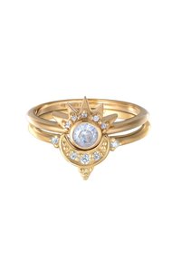 Anillo de oro con una piedra central redonda rodeada de piedras claras más pequeñas, con un diseño puntiagudo en la parte superior y acentos circulares en la parte inferior.
