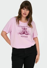 Pink short-sleeve t-shirt featuring a graphic of cowboy boots and text reading "IT'S ABOUT TO GET WESTERN." Soft fabric and relaxed fit.