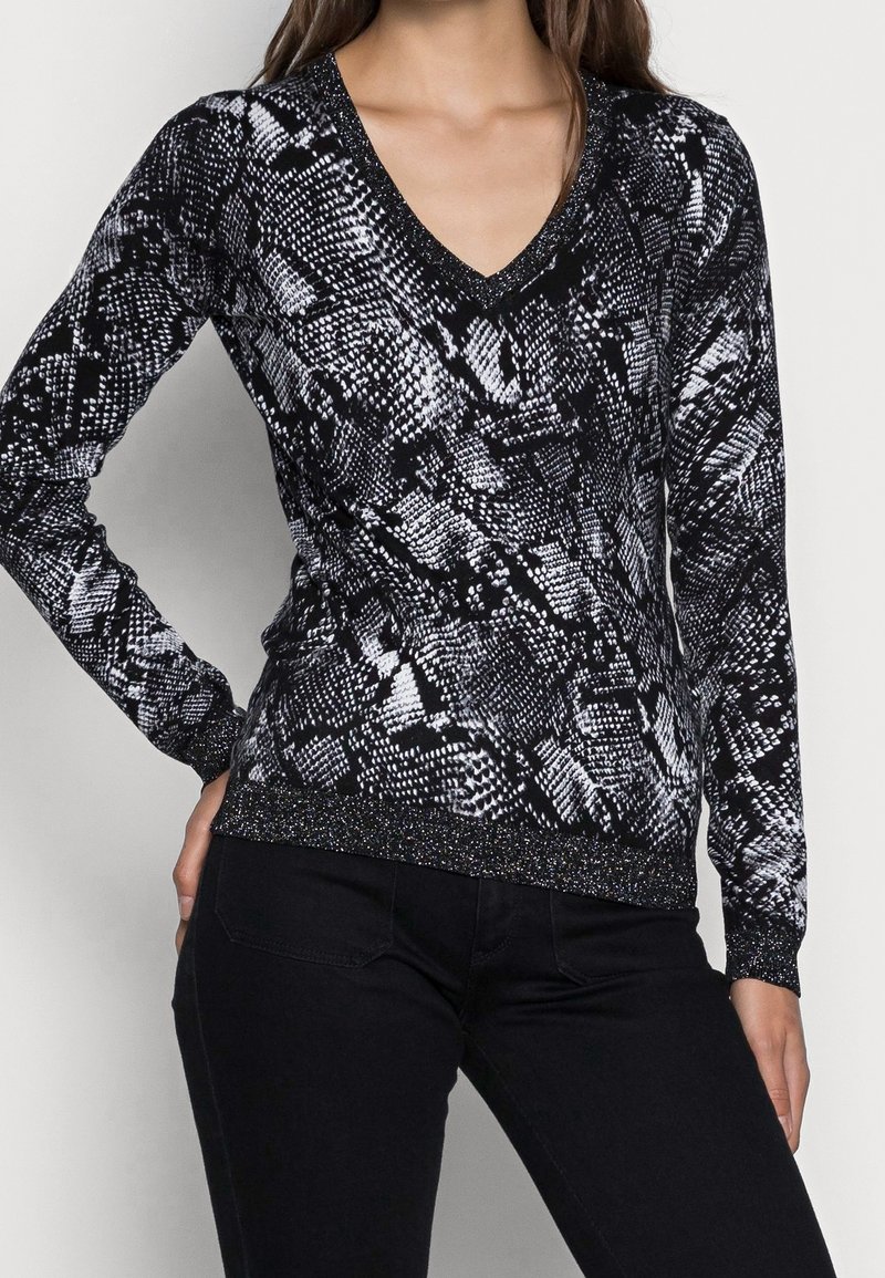 Pull-over à imprimé serpent noir et blanc avec un col en V, des manches longues et une bordure métallique texturée aux poignets et à l'ourlet.